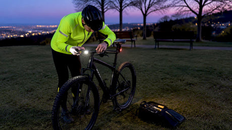 Cyclist adjusting bike lights at dusk