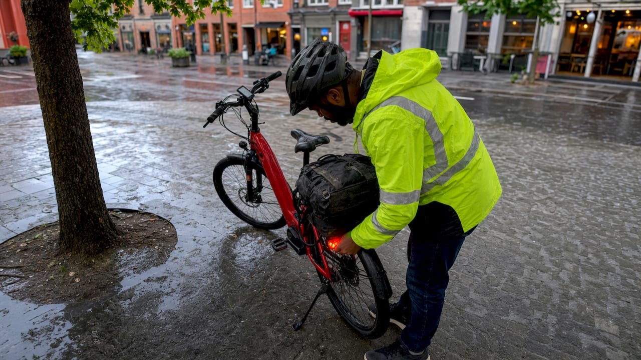 Un cycliste ajuste l'éclairage connecté de son vélo électrique rouge.