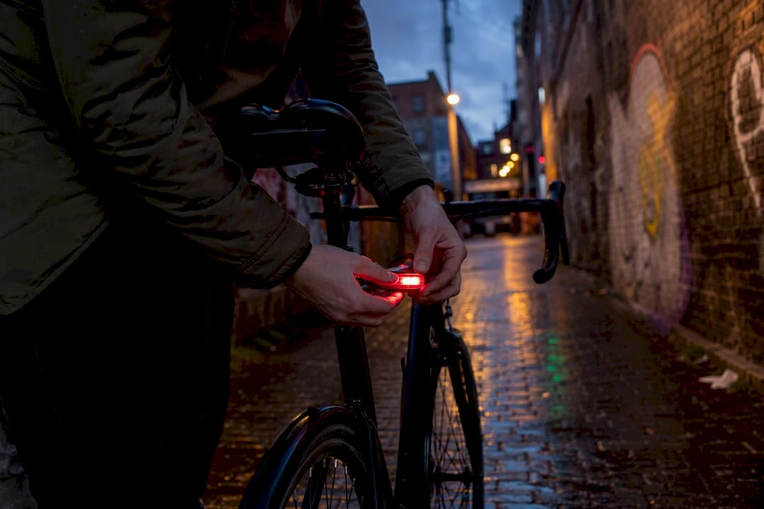 Cycliste réglant le feu arrière de son vélo au crépuscule