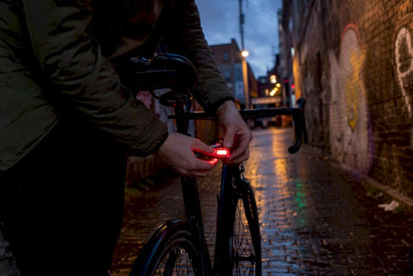 Cycliste réglant le feu arrière de son vélo au crépuscule