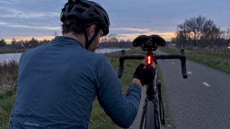 Cyclist checking rear light below saddle