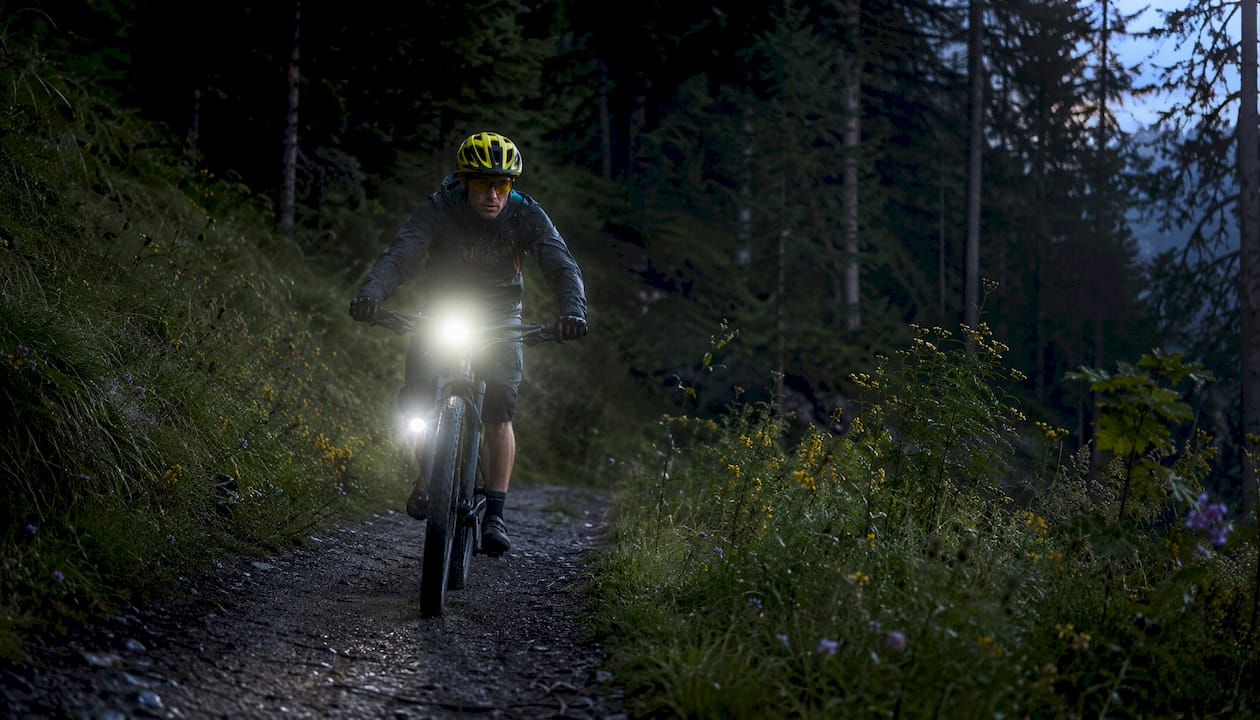Cyclist with adaptive bike lights riding at dusk