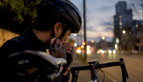 Cyclist adjusting helmet light in urban dusk