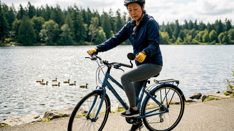 Cyclist sitting on bike adjusting right mirror outdoors