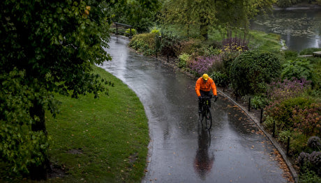 Cyclist wearing waterproof rain gear on wet urban street