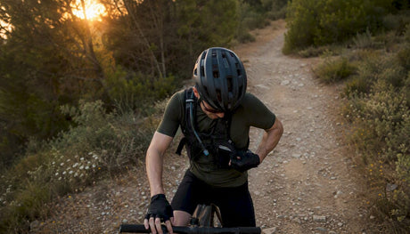 Cyclist adjusting gloves on gravel trail ride