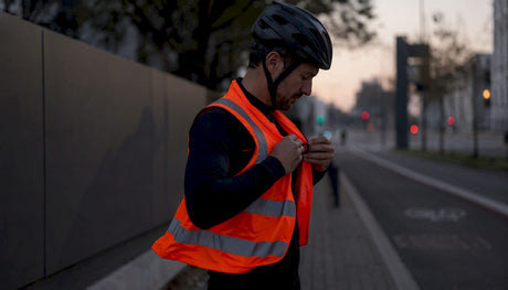 Un cycliste ajuste son gilet fluorescent pour être bien visible en pleine journée.