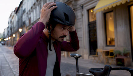 Cyclist adjusting helmet strap on city street