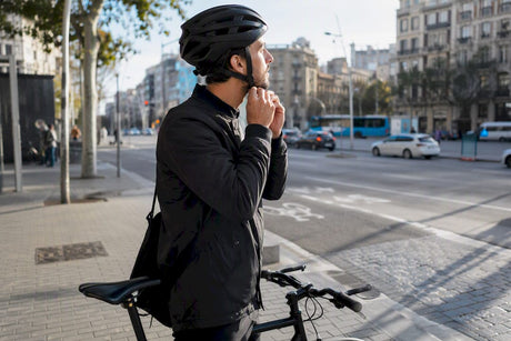 Un cycliste règle la sangle de son casque en pleine ville.