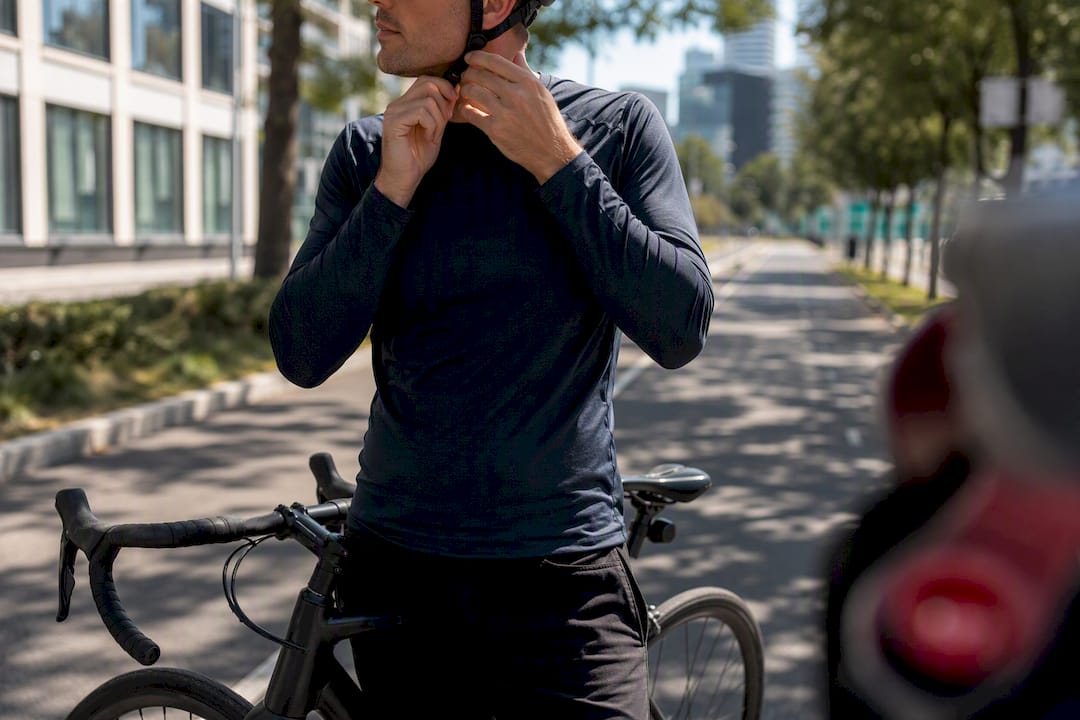 Cycliste attachant la sangle de son casque intelligent sur une piste cyclable urbaine