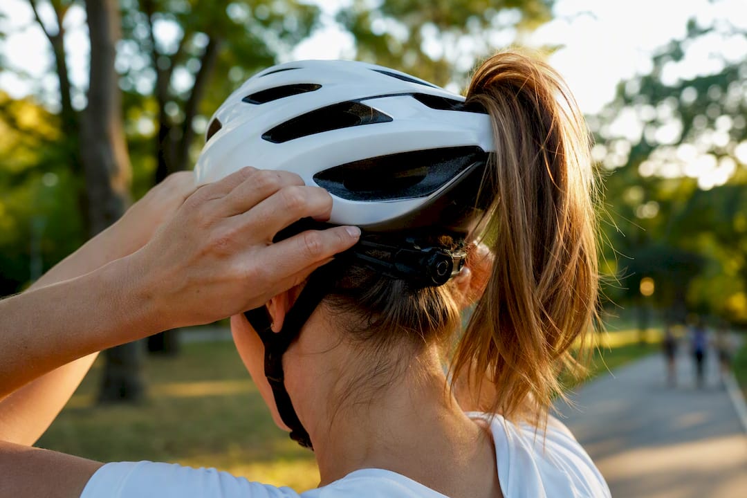 Cyclist adjusting bike helmet with ponytail