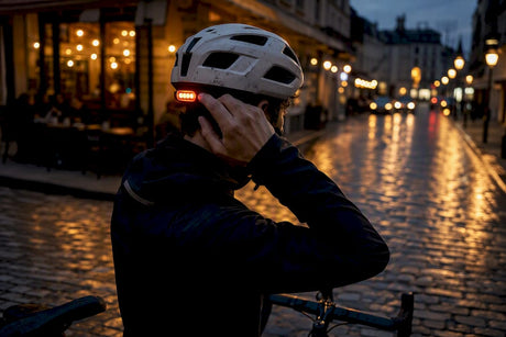 Cyclist adjusting helmet light at dusk