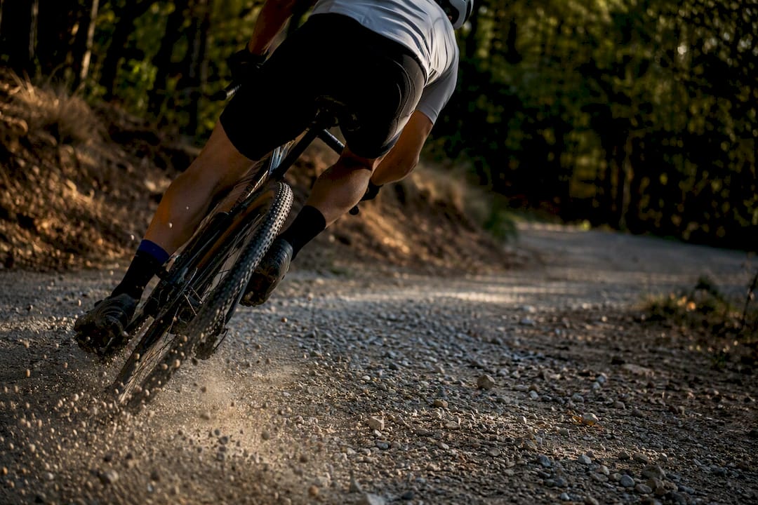 Cycliste sur gravel prenant un virage caillouteux